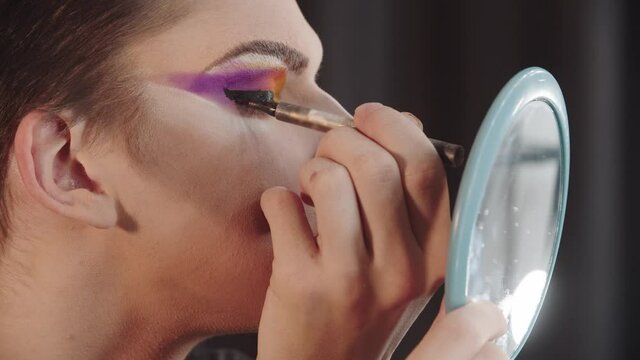 Drag artist - young man applying a thick black eyeliner