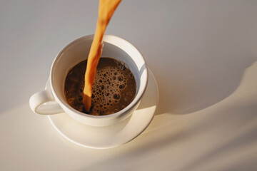 Pouring of coffee in a cup creating splash
