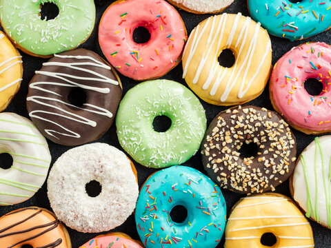 Donuts pattern. Top view of assorted glazed donuts. Colorful donuts with icing as background with copy space. Various colorful glazed doughnuts with sprinkles.