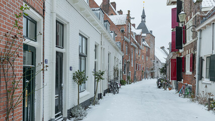 Fototapeta na wymiar A wintry cityscape of the medieval city of Amersfoort in the center of the Netherlands. Buildings and streets are covered with snow. 