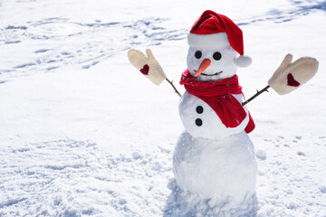 Funny snowman with Santa hat, scarf and mittens outdoors on sunny day. Space for text