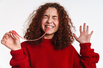 Excited ginger young woman making fun with gummy