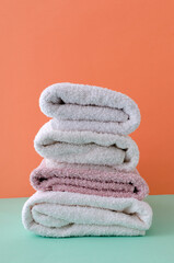 Obraz na płótnie Canvas Vertical image.Stack of white clean towels and pink on on the blue background against orange wall