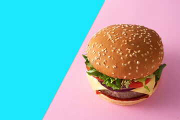 Cheeseburger with beef,tomato, lettuce and onion on pink and blue background. Copy space