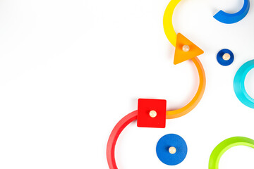 Wooden geometric shapes colorful toy figures composition on white background. Top view