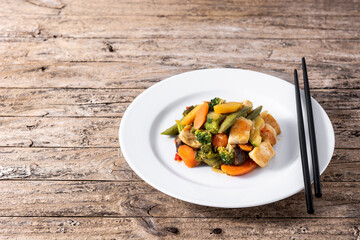 Stir fry chicken with vegetables on rustic wooden table.Copy space