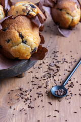 Top view of chocolate muffins, spoon with chocolate shavings, selective focus, on wooden table, vertical