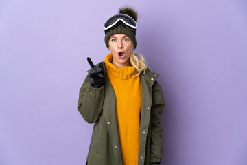 Skier Russian girl with snowboarding glasses isolated on purple background intending to realizes the solution while lifting a finger up