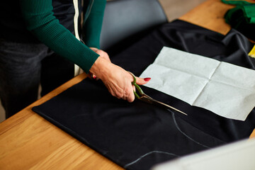 Step by step, Woman dressmaker hands cutting material with scissors on table