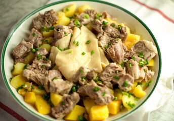 Beshbarmak - traditional hot meat dish of the Turkic-speaking peoples. A dish of Asian cuisine. Meat dish close-up. Meat, dough, potatoes, green onions. Delicious hearty homemade food.