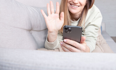 Young woman lying on the sofa when having video call with her friend.