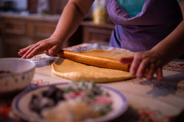 Obraz na płótnie Canvas the housewife spreading the dough with a rolling pin. preparation of homemade cakes