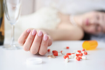 Obraz na płótnie Canvas Bride in wedding dress lying on couch with handful of pills in her hand closeup