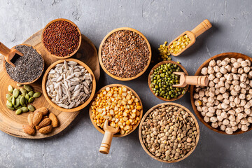 Assortment of beans, seeds, legumes on grey concrete background.