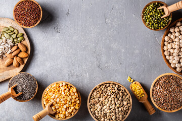 Assortment of beans, seeds, legumes on grey concrete background.