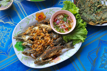 Top view of Thai style deep fried Flathead mullet fishes with garlic eat with spicy and sour dip 
