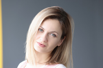 Portrait of young blonde woman on gray background