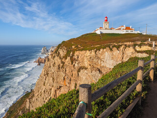Cabo da Roca lighthouse on the hill in the blue sky background, overlooking the Atlantic Ocean....