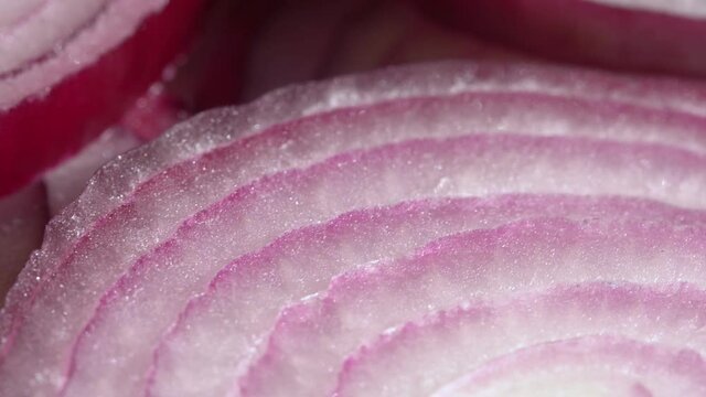 Sliced red onion rings rotating in 4K. Closeup top view of healthy food background with vegetable of rich vitamin