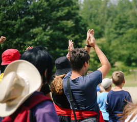 Fototapeta premium Many children of boys and girls emotionally support or cheer on the team with raised hands and yelling at the summer camp in games competition