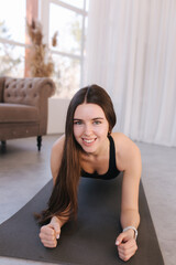 Attractive fit woman doing yoga plank at home. Training season is open. Woman use little dumbbells