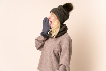 Young woman with winter hat over isolated background shouting with mouth wide open