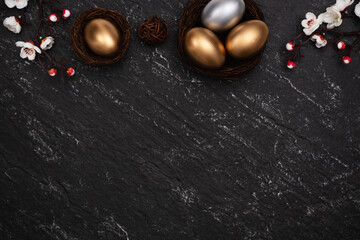 Golden and silver Easter eggs with flower on black background.