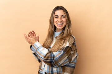 Young caucasian woman isolated on beige background applauding