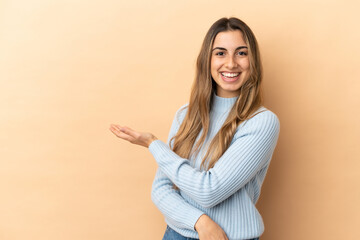 Young caucasian woman isolated on beige background presenting an idea while looking smiling towards