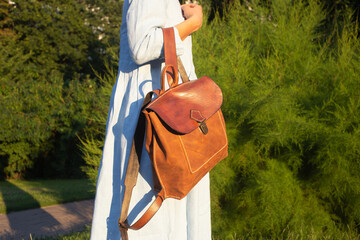 Girl in blue dress wears leather fashion handmade bag. Leather backpack craft product.