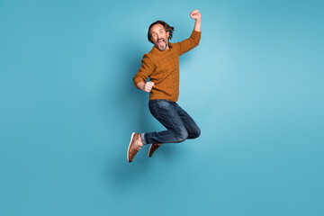 Full size photo of mature handsome excited crazy smiling man jumping in success victory isolated on blue color background