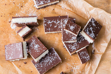 Organic raw vegan coconut bars with chocolate on kitchen table