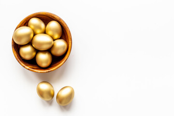 Golden Easter eggs in wooden bowl. Wealth and good luck concept.
