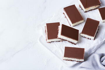 Organic raw vegan coconut bars with chocolate on kitchen table