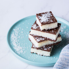 Organic raw vegan coconut bars with chocolate on kitchen table