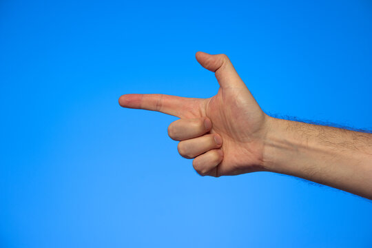 Caucasian male hand making a fake pistol gesture studio shot isolated on blue