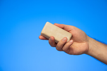 Bar of soap held in hand by Caucasian isolated on blue background studio shot