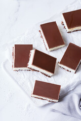 Organic raw vegan coconut bars with chocolate on kitchen table