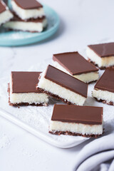 Organic raw vegan coconut bars with chocolate on kitchen table