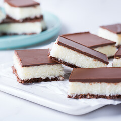 Organic raw vegan coconut bars with chocolate on kitchen table