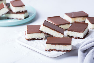 Organic raw vegan coconut bars with chocolate on kitchen table
