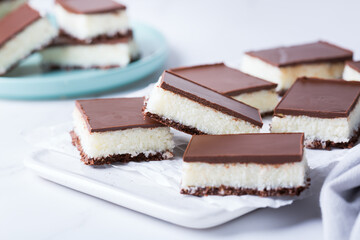 Organic raw vegan coconut bars with chocolate on kitchen table