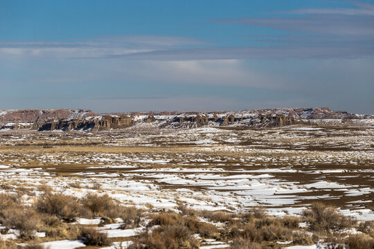 Open snow covered valley in New Mexico desert with rocky hills with clear sky