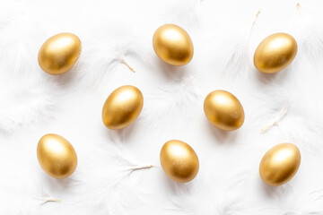 Golden Easter eggs with white feather. Top view decoration