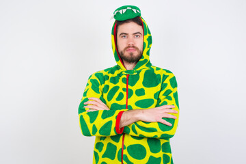 Serious pensive young caucasian man wearing a pyjama standing against white wall feel like cool confident entrepreneur cross hands.