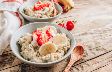 Quinoa porridge with coconut milk and fresh strawberries on wooden rustic background. Healthy Lactose and Gluten Free Breakfast.