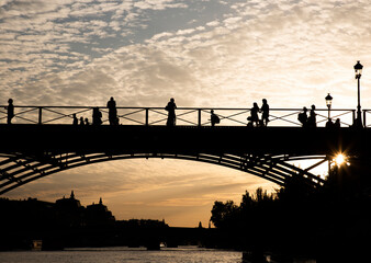 Group of people on bridge above river at sunset