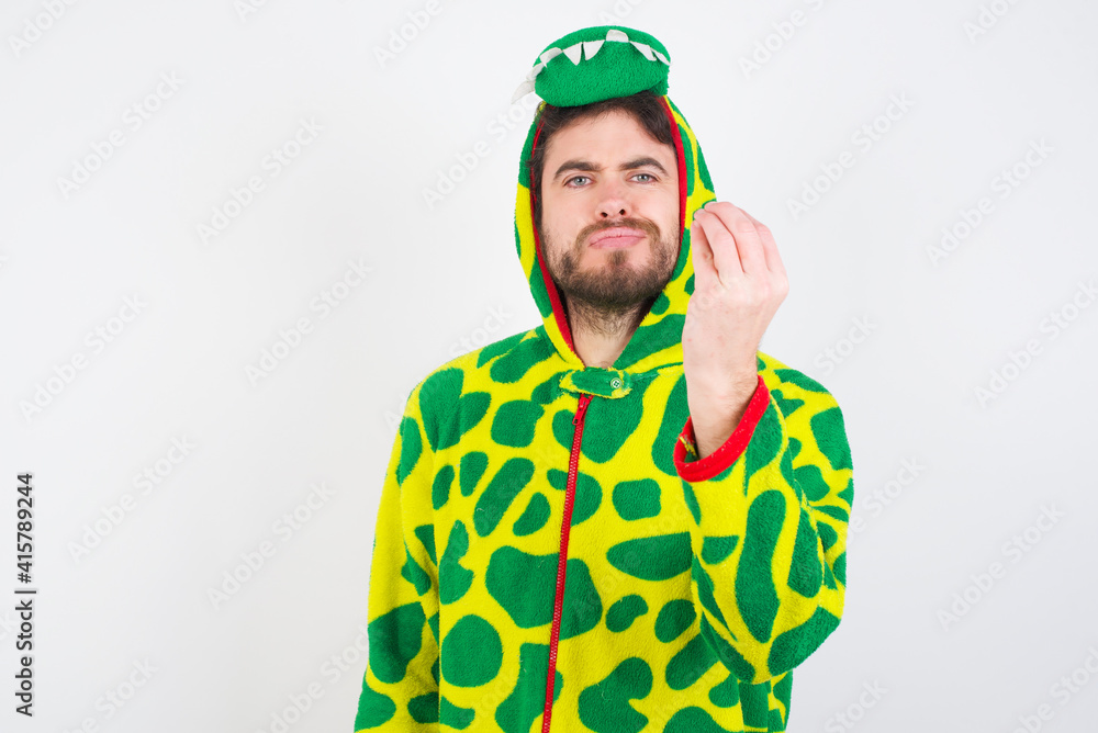 Sticker young caucasian man wearing a pyjama standing against white wall angry gesturing typical italian gesture with hand, looking to camera