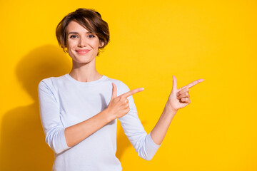 Photo of lady indicate forefingers empty space look camera wear white shirt isolated yellow color...