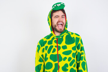 Fototapeta premium young caucasian man wearing a pajama standing against white wall winking looking at the camera with sexy expression, cheerful and happy face.